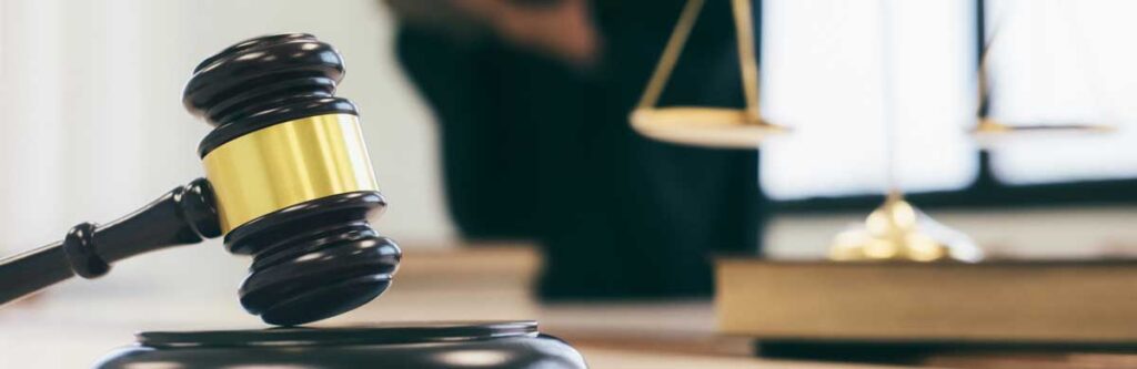 A gavel rests on a desk, representing legal proceedings.