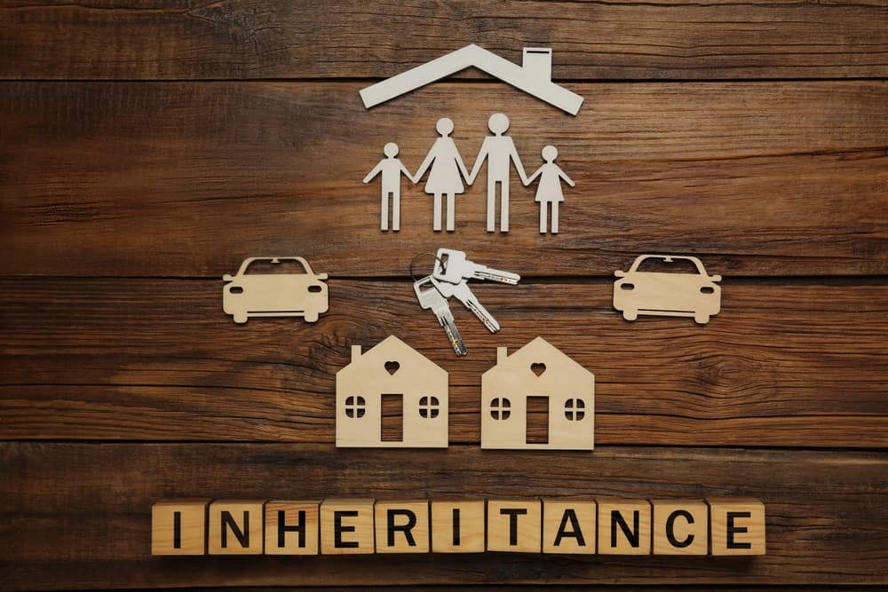 Word Inheritance made with cubes and different cutouts on wooden background, flat lay
