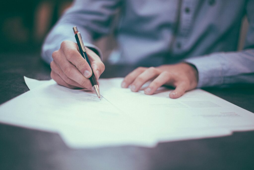 Person signing a legal document as part of updating a power of attorney or other estate planning paperwork.
