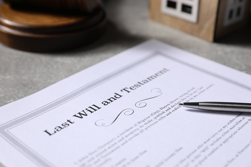 Last Will and Testament, house model, gavel and pen on grey table, closeup