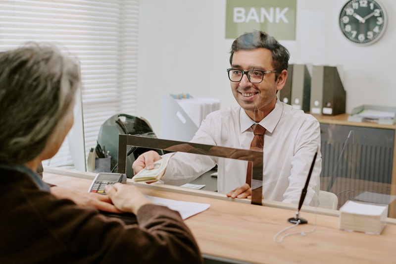 A bank teller discussing different account options with an older banking client.