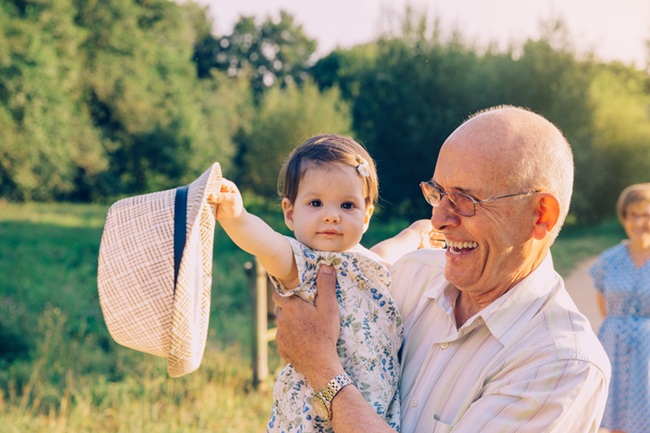 An elderly man is smiling while holding his granddaughter. He is happy knowing that his estate plan is current and will take care of his family.